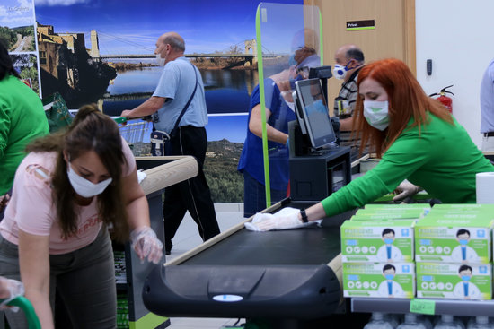 A woman working in a shop in Amposta cleans the checkout area, May 13, 2020 (by Jordi Marsal)