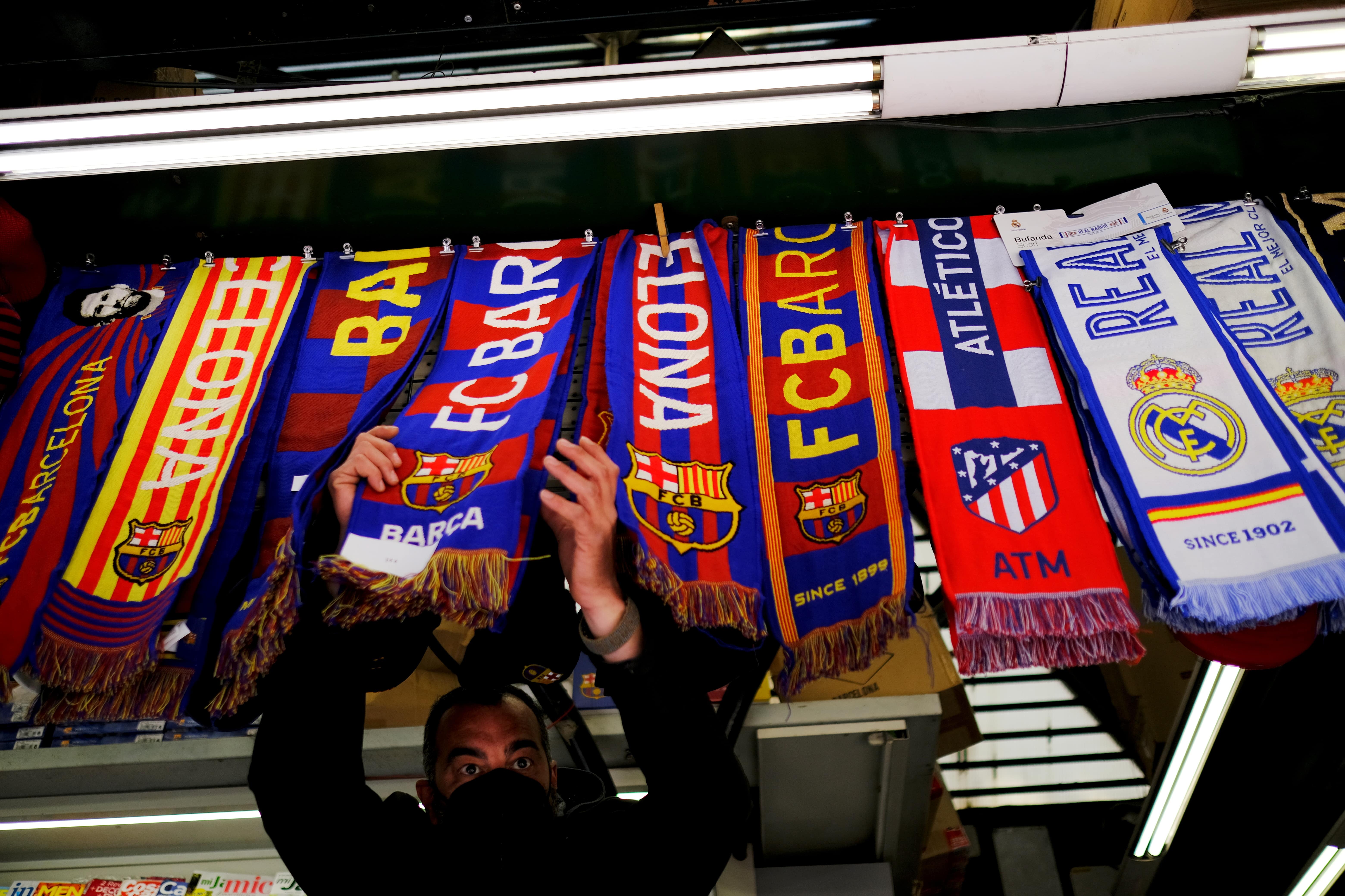 A stall selling scarves of FC Barcelona, Atletico Madrid, and Real Madrid (image from REUTERS/Nacho Doce)