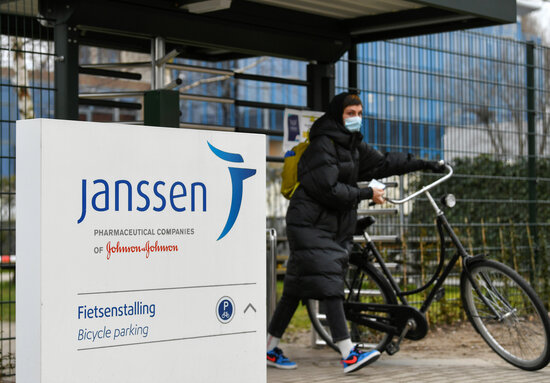 A woman walks with a bicycle outside a Janssen branch in the Netherlands (by REUTERS / Piroschka van de Wouw)