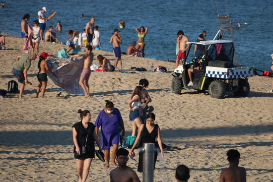 A police vehicle asks beachgoers in Barcelona to leave before closing the beach for Sant Joan last year, June 23, 2020 (by Pau Cortina)