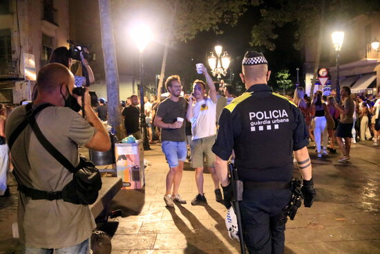 A local police officer attempts to break up groups of people drinking on the street in Barcelona during Catalonia's fifth wave of Covid-19, July 10, 2021 (by Laura Fíguls) 