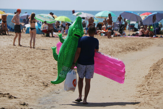 A man carries inflatables down to the beach in Salou, July 27, 2021 (by Ariadna Escoda)