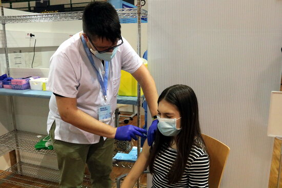 A nurse administering a coronavirus vaccine (by Salvador Miret)