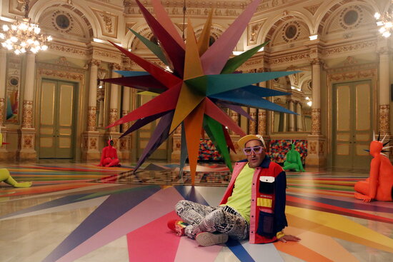Artist Okuda San Miguel sits in front of his installation in Sala Miralls, inside Barcelona's iconic opera hall, Licue (by Pere Francesch)