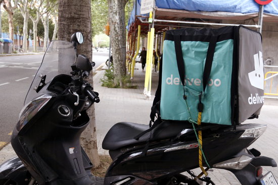 A motorcycle with a Deliveroo delivery box on the back of it (by Sílvia Junyent)