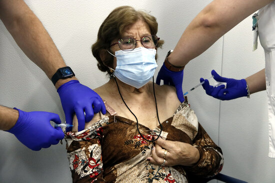 A woman is given a Covid-19 booster shot and a flu vaccine at the same time (by Oriol Bosch)