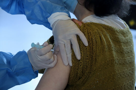 A woman is given a Covid-19 vaccine (by Albert Lijarcio)