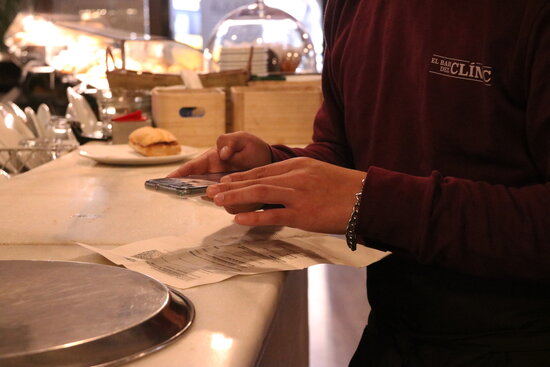 A waiter scans a Covid certificate, Barcelona, December 3, 2021 (by Aina Martí)