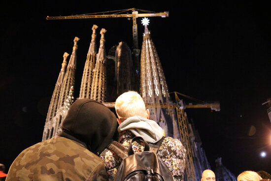 People take photos at the Sagrada Família as the star atop the tower of the Virgin Mary is lit up for the first time, December 8, 2021 (by Jordi Bataller)