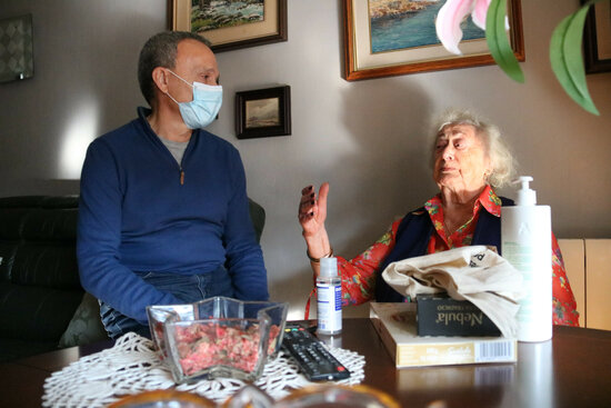 Leonor chats to Emilio, one of the volunteers, at her home in Barcelona, December 17, 2021 (by Eli Don) 