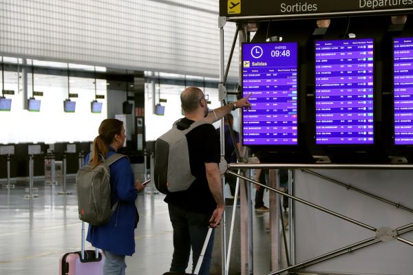 People check information boards at Barcelona airport