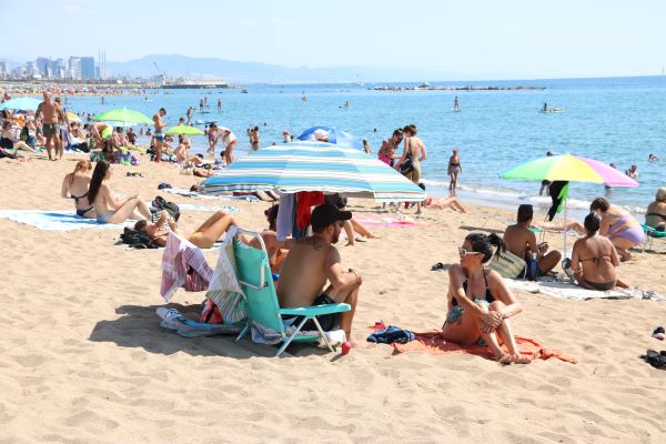Bathers enjoy the sun on a beach in Barcelona, July 2022 (by Natàlia Segura)