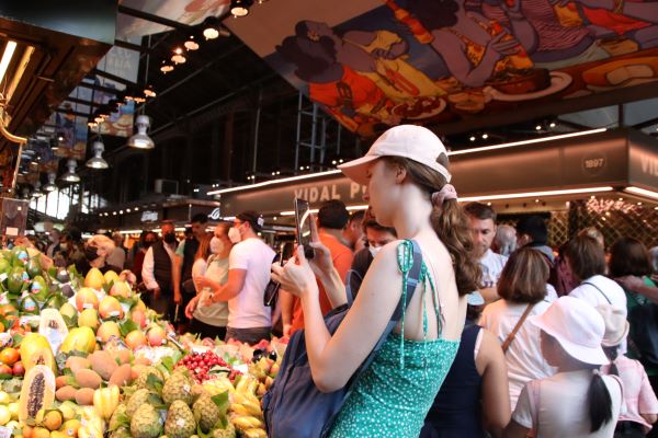 A woman takes a photo of a fruit stall at La Boqueria market in Barcelona