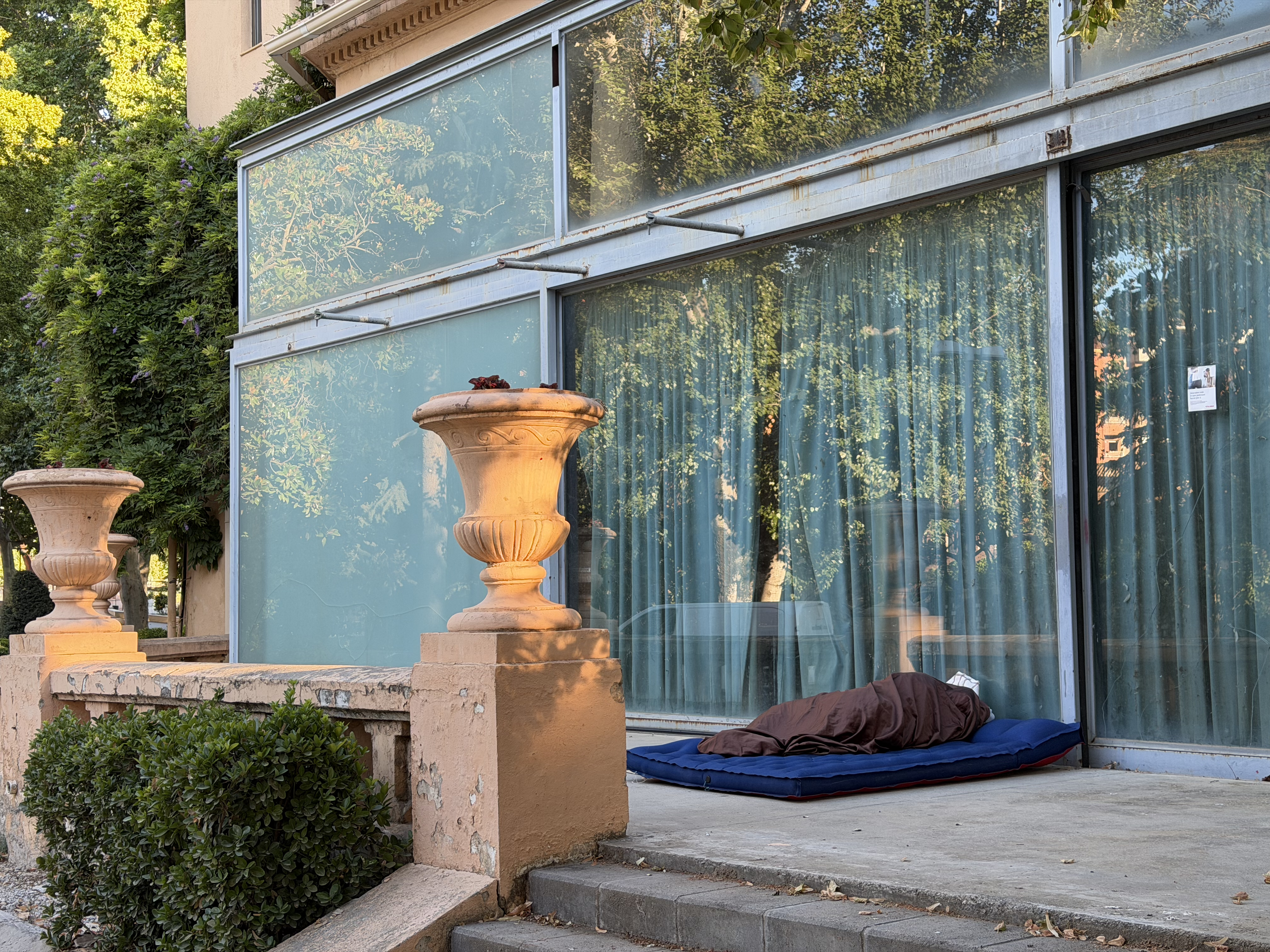 A homeless person sleeping on the ground next to the modernist villa of the Champs Elisis, in Lleida.