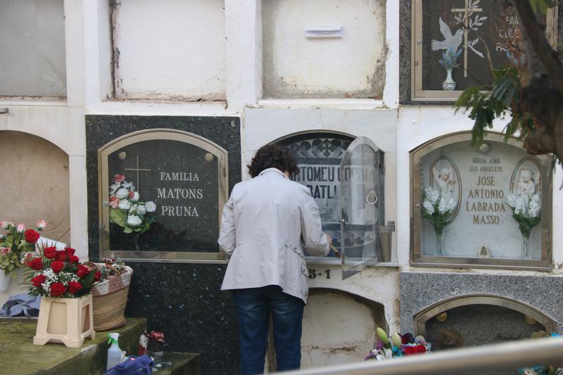 A person cleans a niche in a cemetery on All Saints’ Day