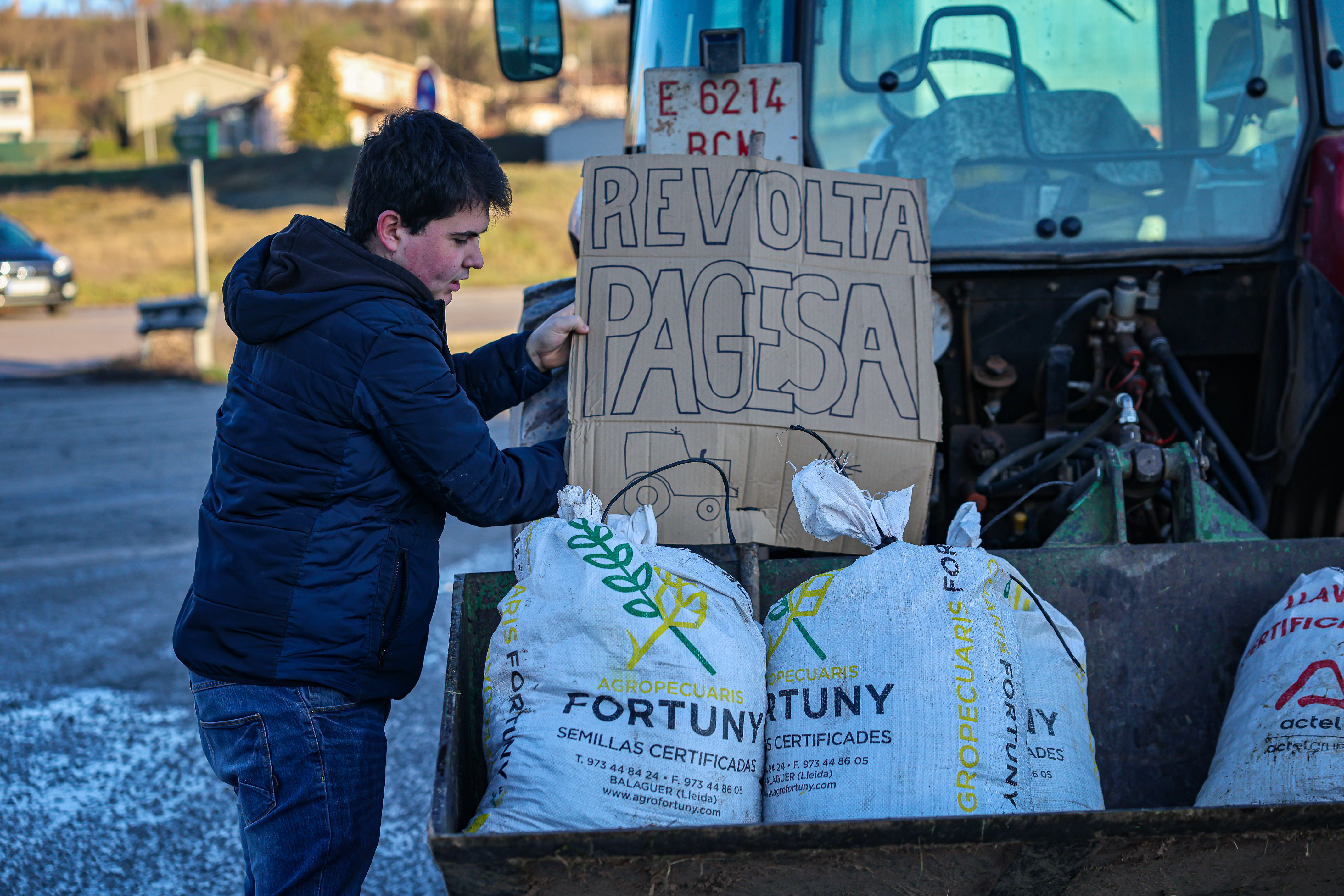 A farmer places a 'Farmer revolution' sign on a tractor ahead of a protest