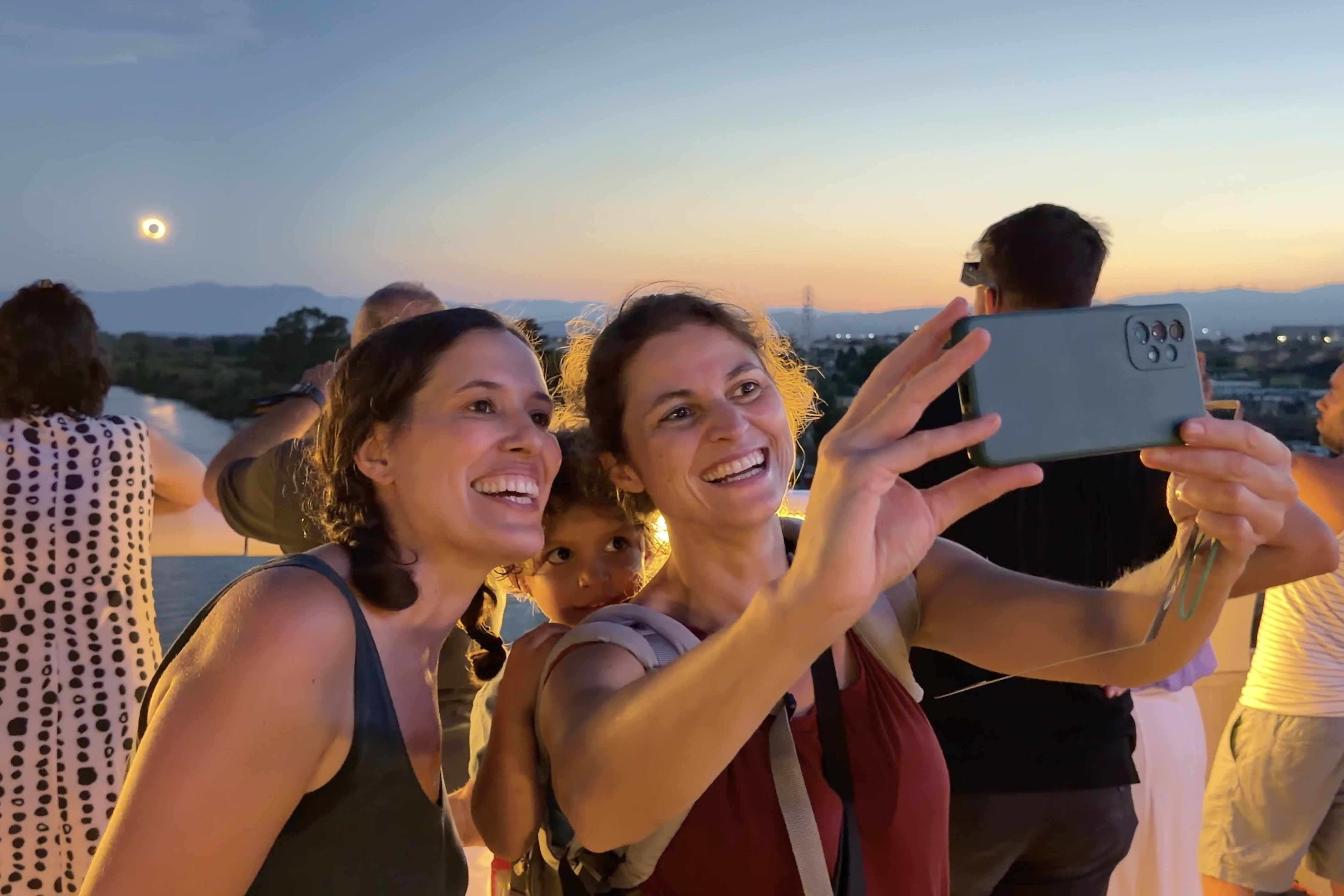 Two women take a selfie with the total eclipse in the background