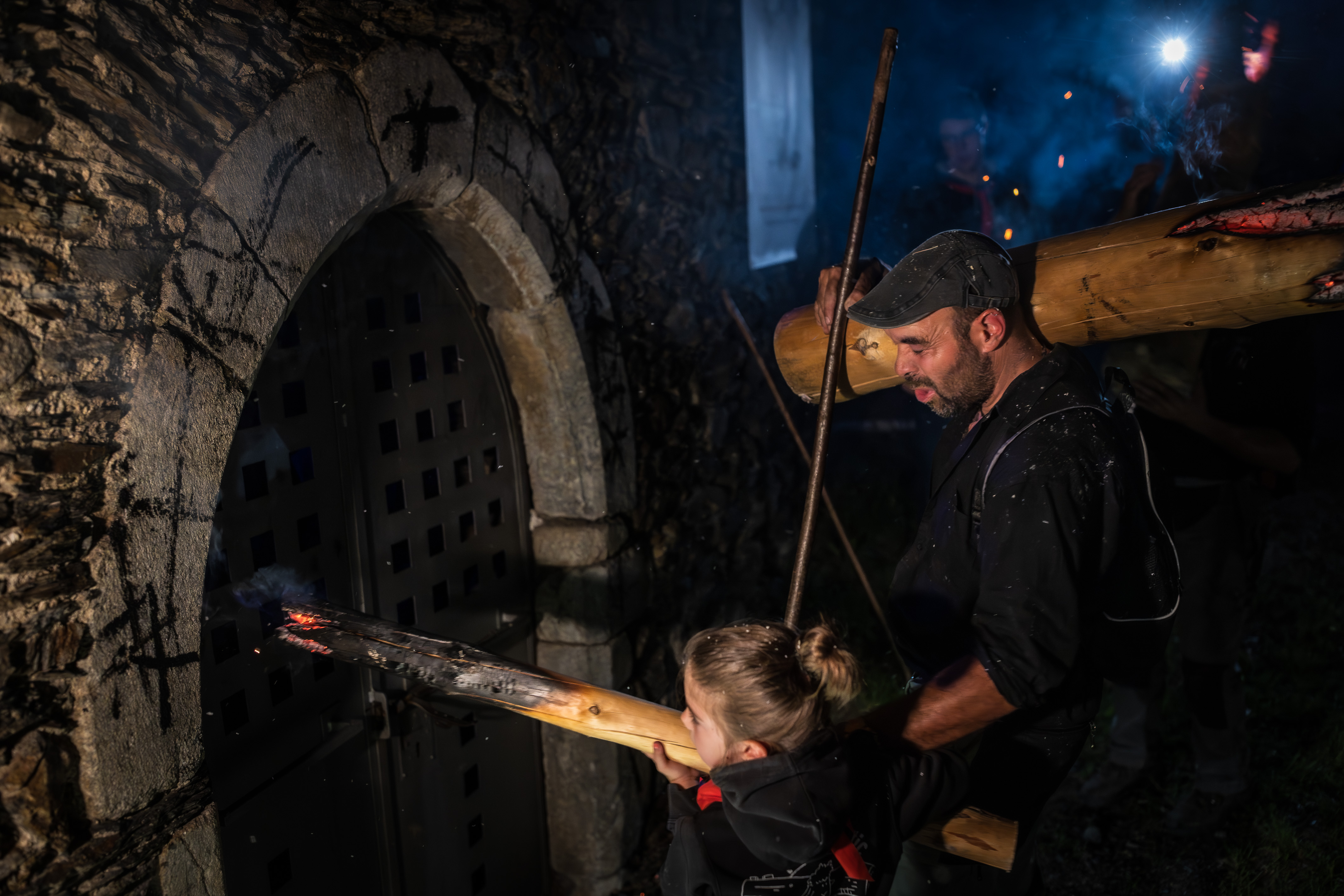 A girl making three crosses at the cemetery gate in Isil, with the falla lit, in memory of the people who are no longer there.