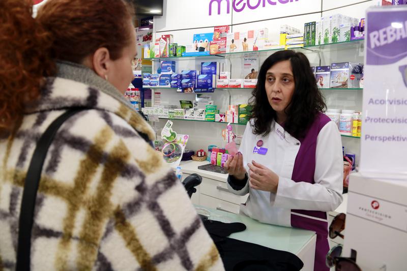 A pharmacist shows a menstrual cup to a woman