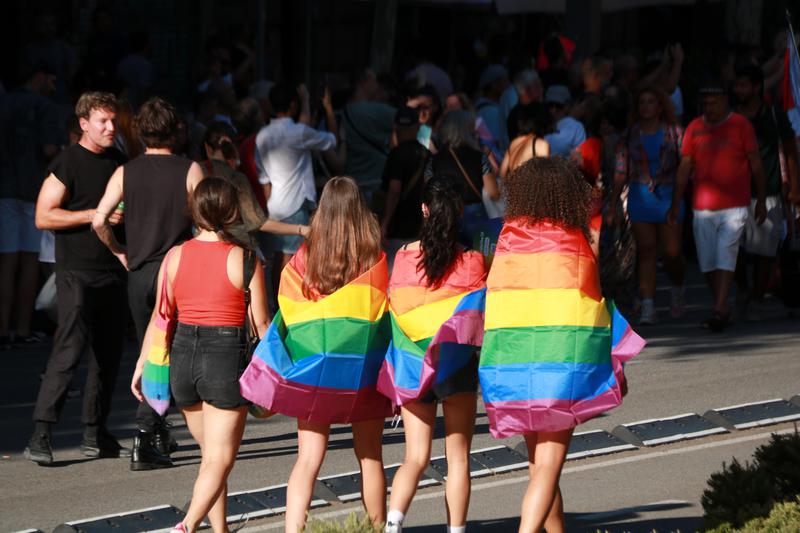 Four girls wearing rainbow flags at Pride Barcelona
