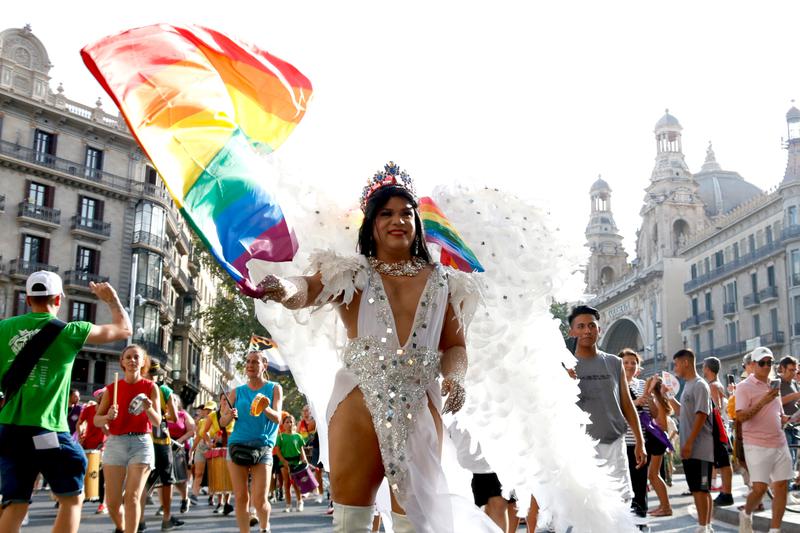 A person dressed like an angel during the Pride parade in Barcelona waves an LGBTI+ flag on July 20, 2024