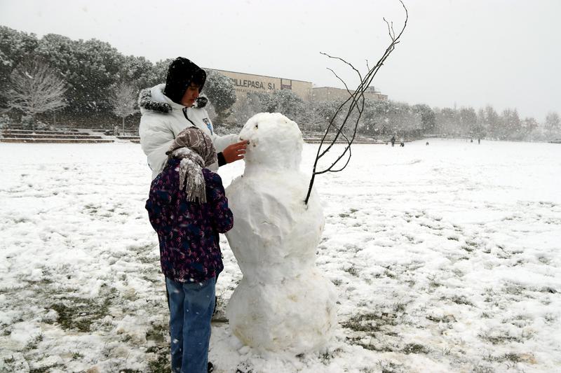 A family build a snowman in the Igualada central park