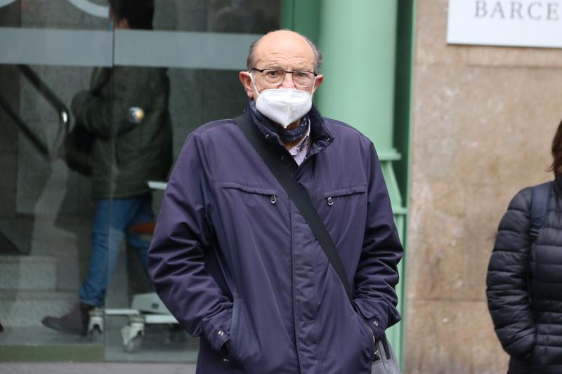 A man leaves a hospital wearing a face mask