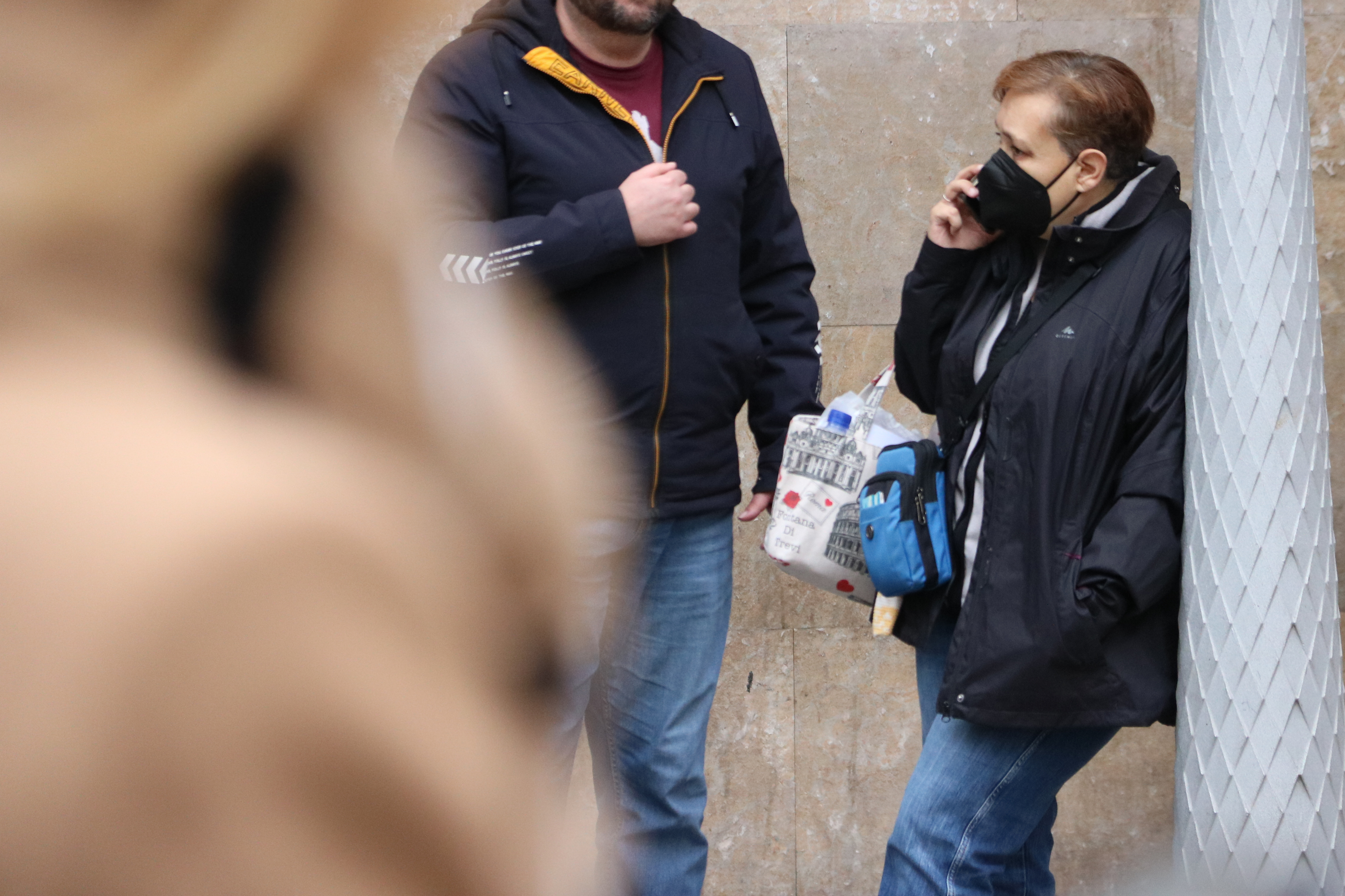 A woman outside Hospital Clínic speaking on the phone while wearing a mask
