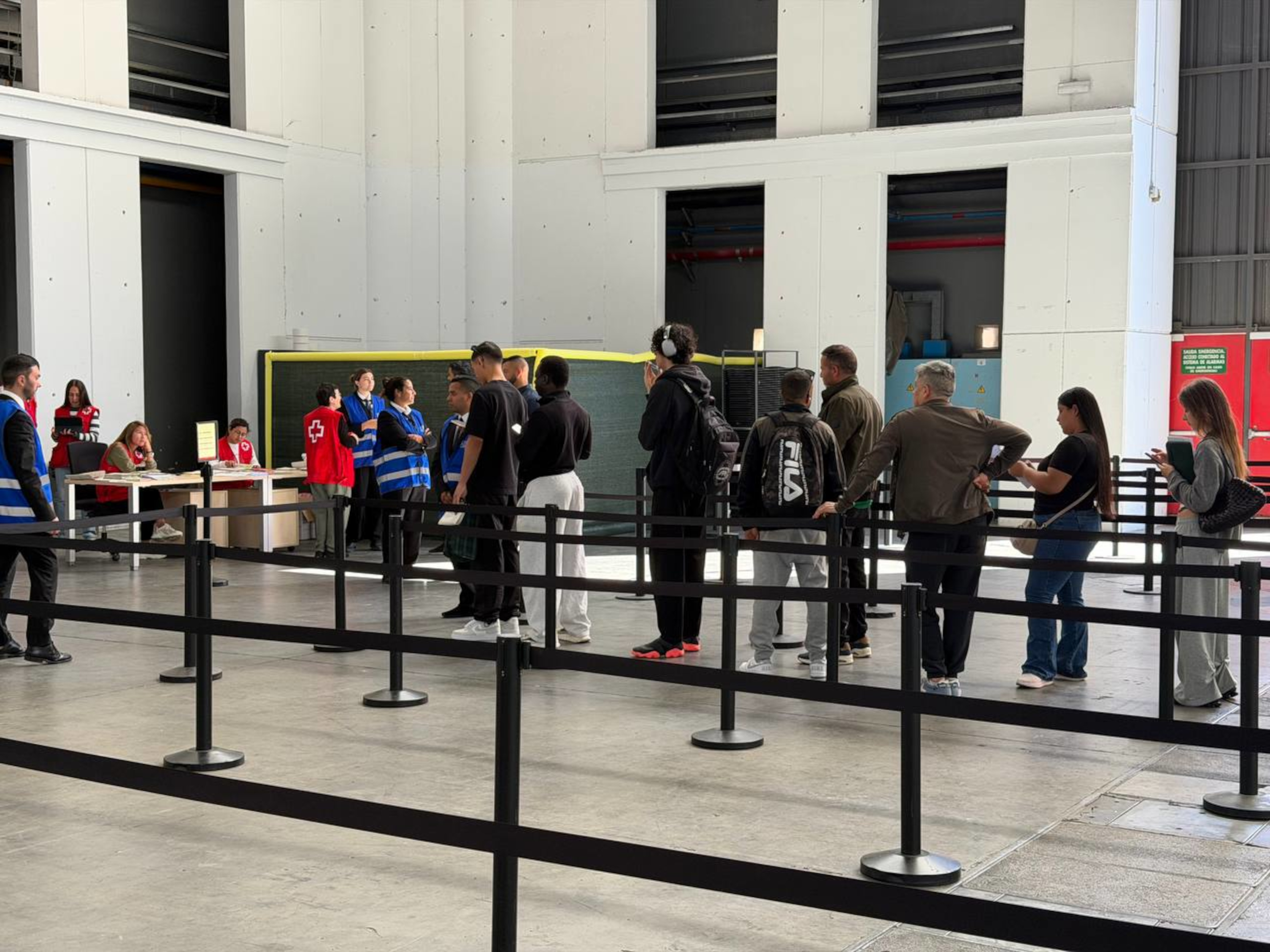 People queue for the migrant regularization process desks at the Fira de Montjuïc in Barcelona