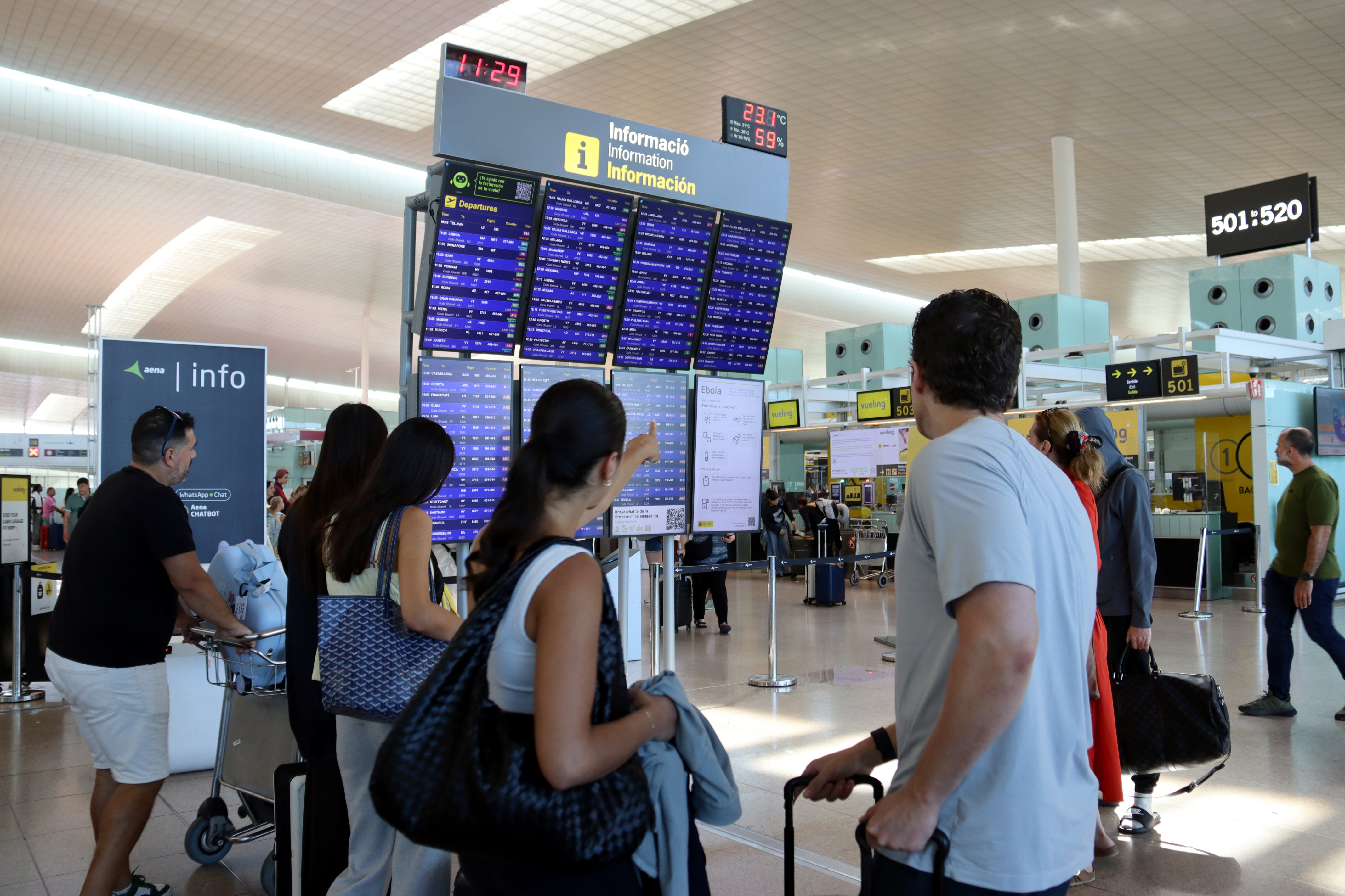 Passengers checking the flight information board at Barcelona Airport