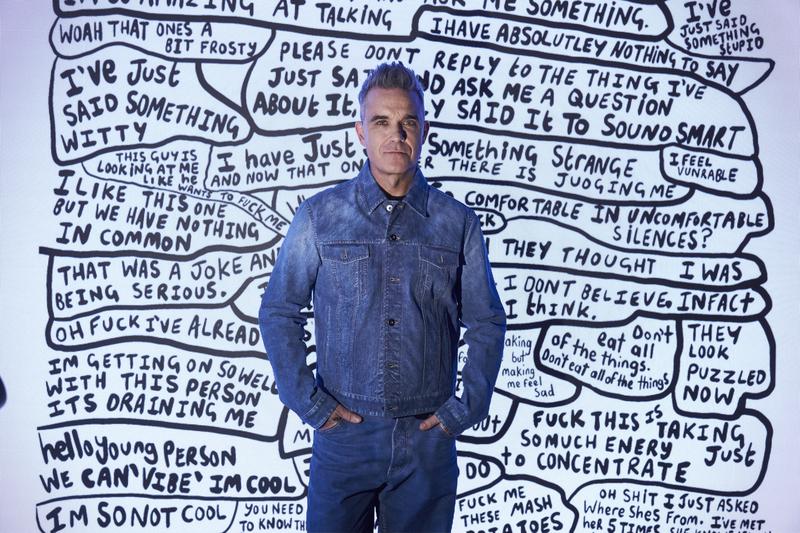 Robbie William in front of one of hist paintings