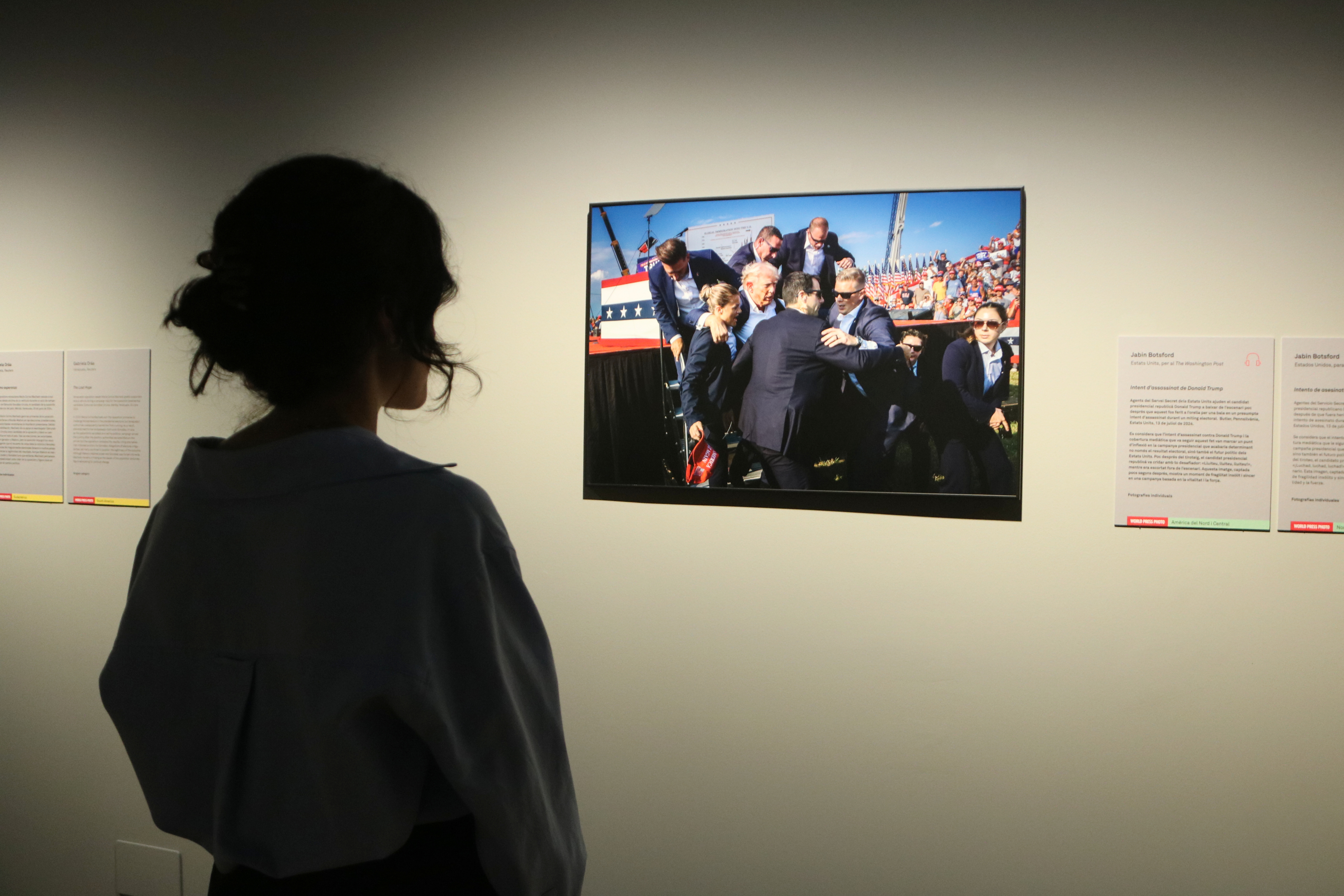 A visitor looks at a photograph in the immediate aftermath of the assassination attempt of Donald Trump at the 'World Press Photo 2025' exhibition in the CCCB