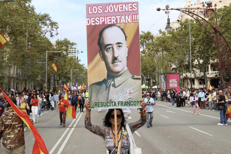 A woman holds a poster with Spanish dictator Francisco Franco's portrait during a demonstration in Barcelona on October 12, 2025