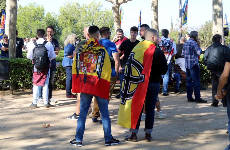 Far-right demonstrators in Montjuïc wearing a Franco-era Spain flag and another flag with a white nationalist symbol