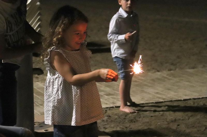 A little girl holding a 'bengala' during Sant Joan 2022 on Roses beach