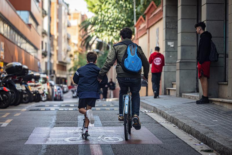 Two children riding a bike and a scooter in Barcelona