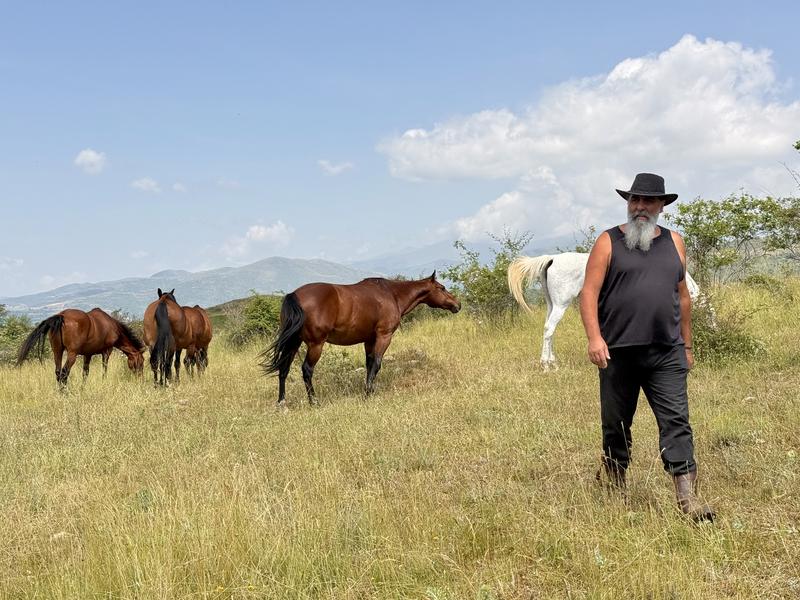Pere Cases, manager of Cavalls Wakan, a horse boarding facility in Montcortès in the Pyrenees, with horses in the background