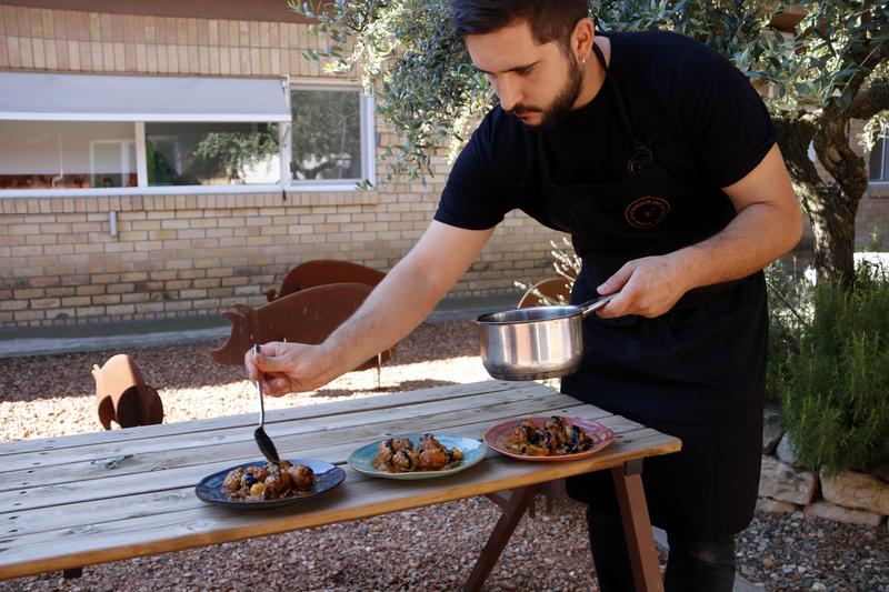 A cook preparing a dish of meatballs with cuttlefish