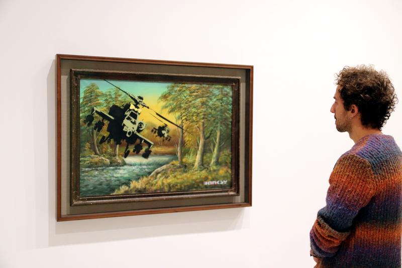 A person gazes at 'Happy Choppers,' by the British artist Banksy, at the Moco Museum Barcelona