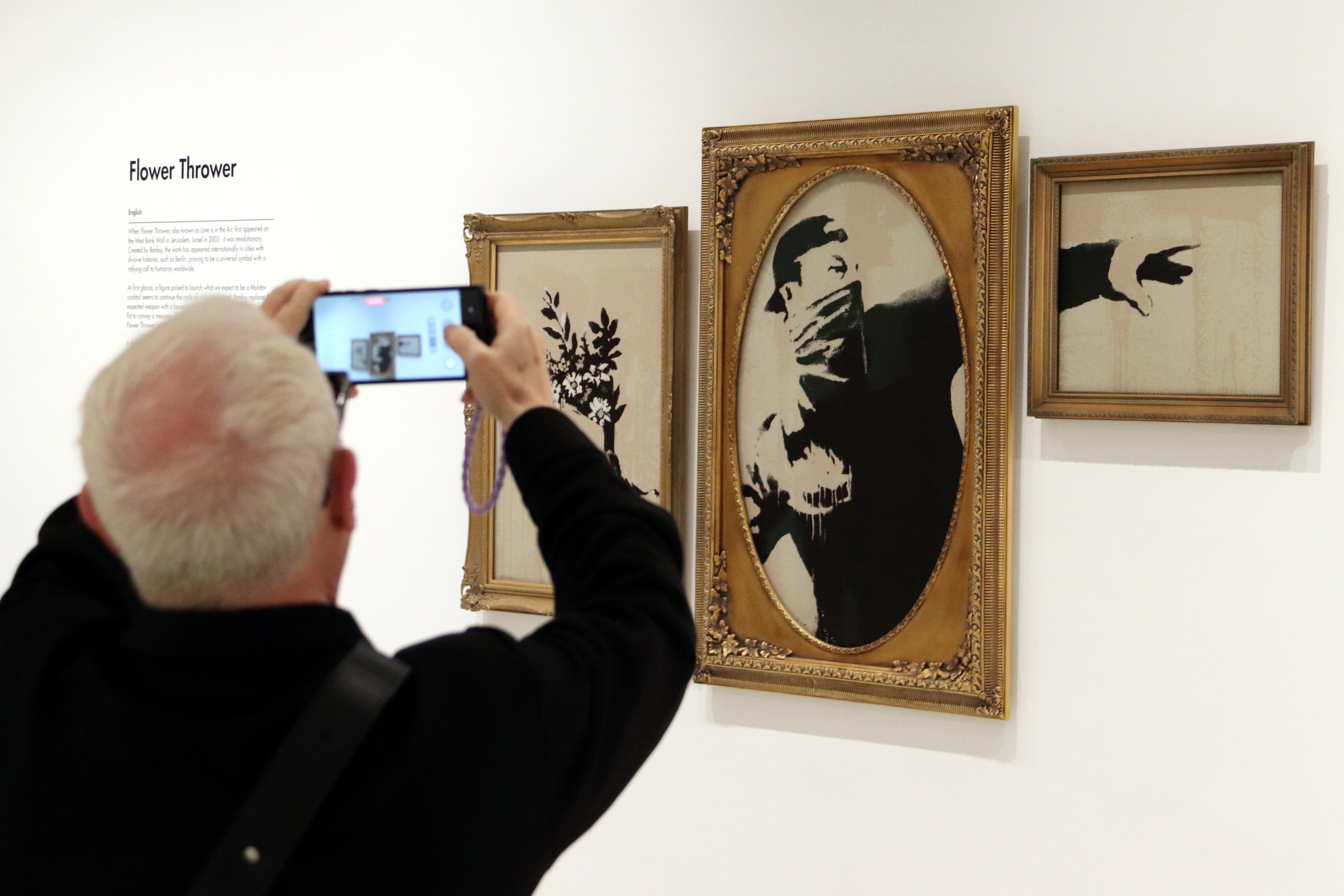 A person photographs the artwork 'Flower Thrower' by the British artist Banksy at the Moco Museum Barcelona