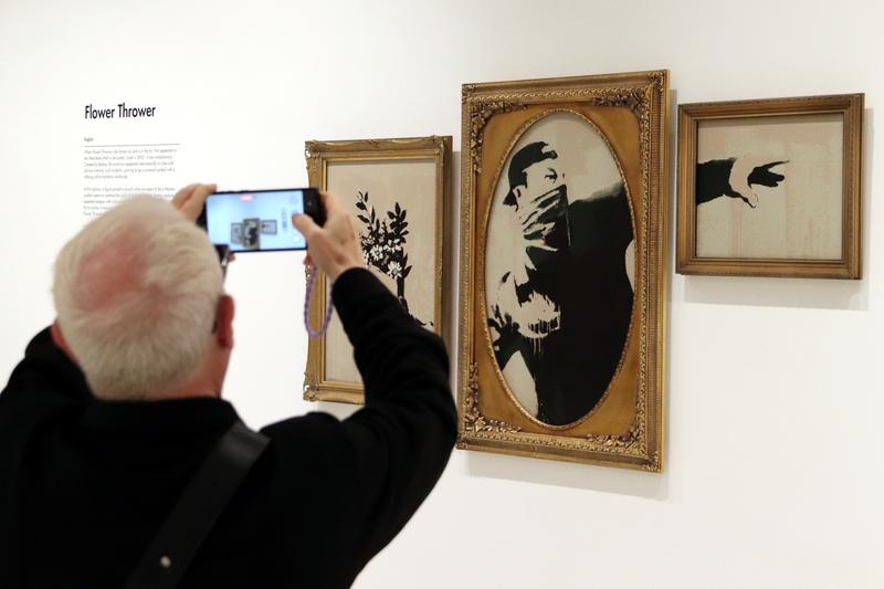 A person photographs the artwork 'Flower Thrower' by the British artist Banksy at the Moco Museum Barcelona
