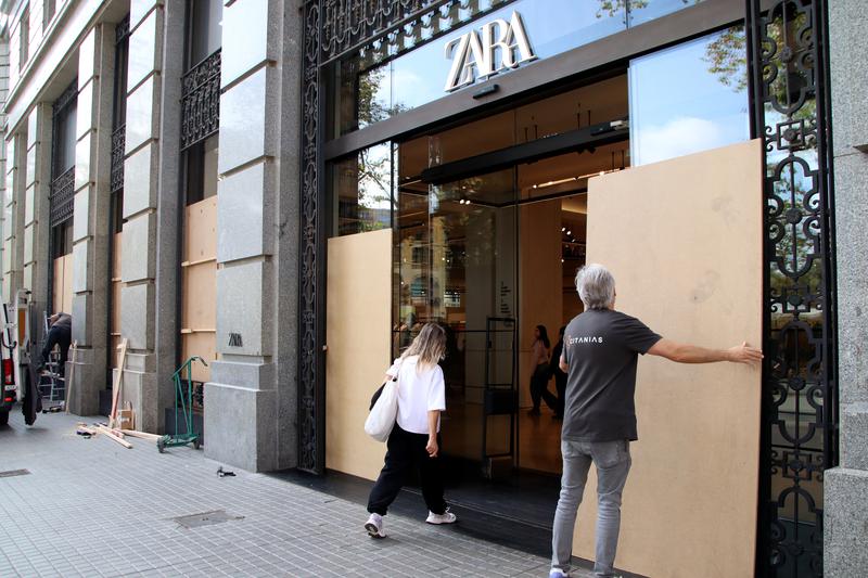 Staff place wooden boards over windows at Zara on Plaça Catalunya