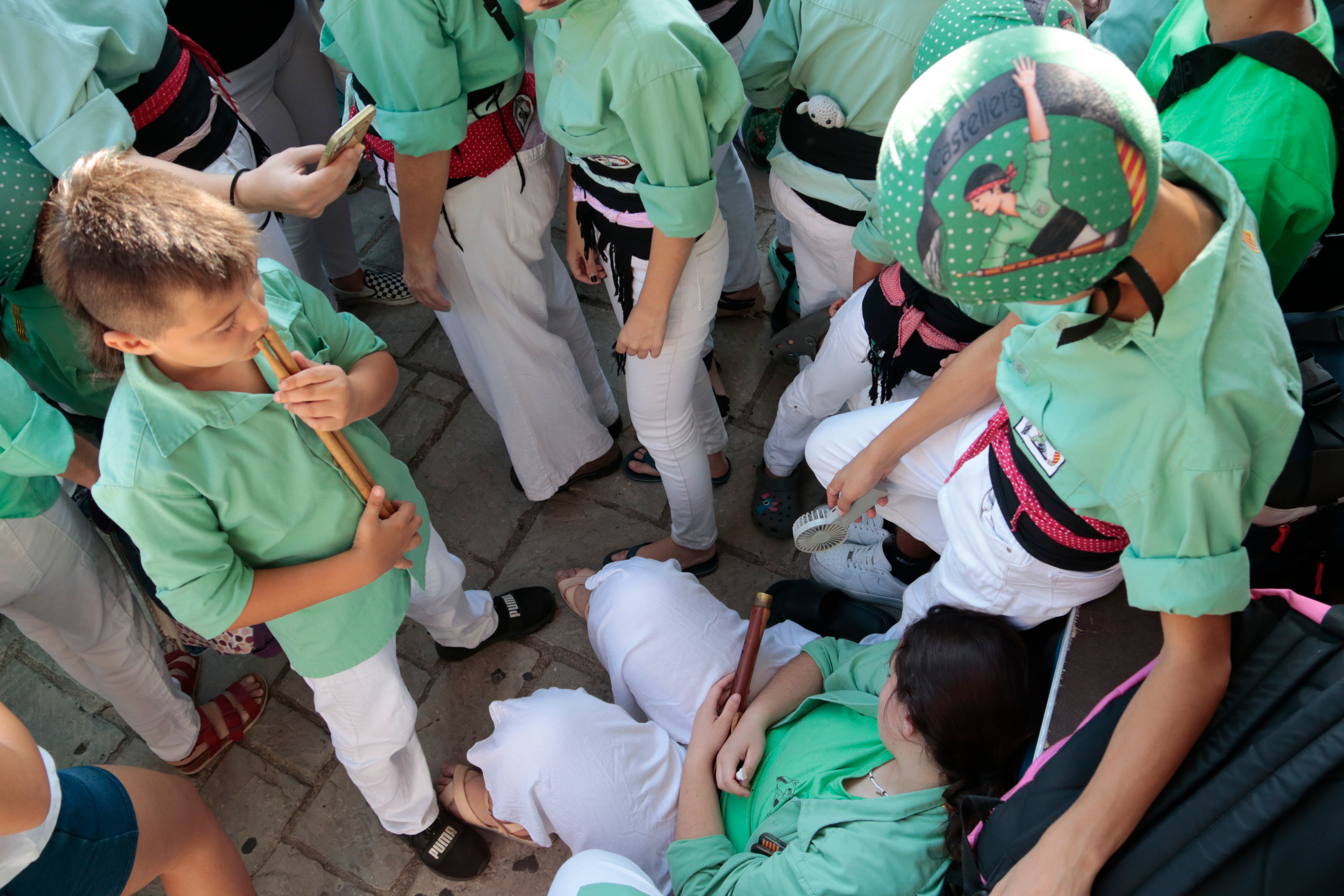 Young members of the Castellers de Mollet try to beat the heat with a small fan during the Castells Competition in Torredembarra.