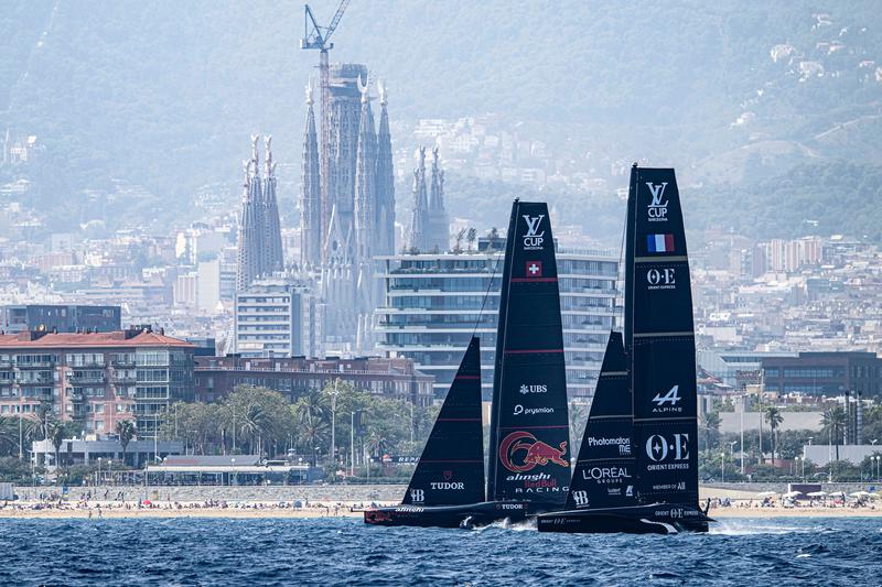 America's Cup teams Orient Express and Alinghi Red Bull Racing sailing in front of Barcelona's Sagrada Família ahead of the sailing competition