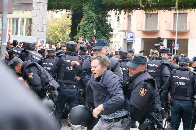 Spanish police officers tackling a voters in Girona's Escola Bruguera on October 1, 2017