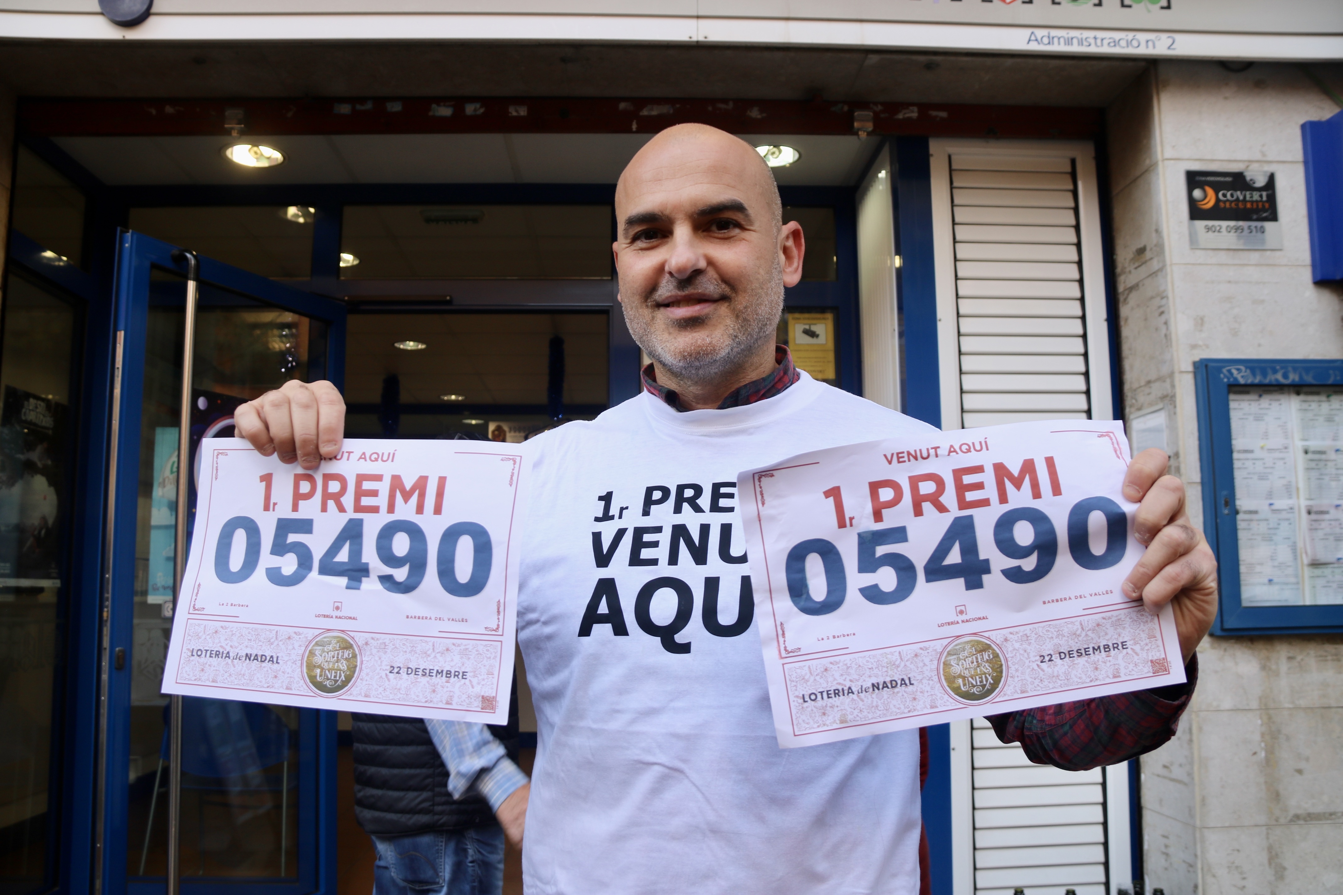 Alfonso López, responsible of Barberà del Vallès lottery retail holds two posters reading he has sold the 'Fat One' of the Christmas lottery on December 22, 2022