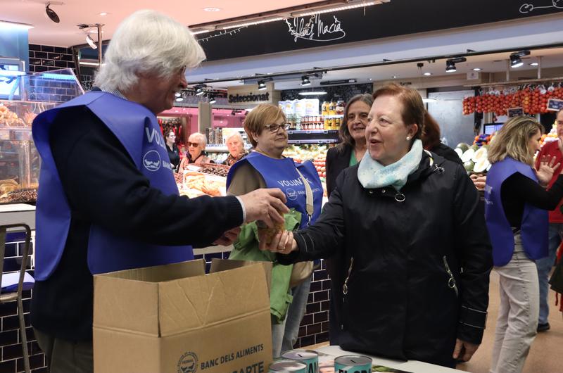 A volunteer receives a jar of chickpeas during the launch of the Gran Recapte at the Ninot Market.=