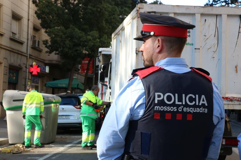 A police office observes as refuse collectors remove a container where human remains were discovered