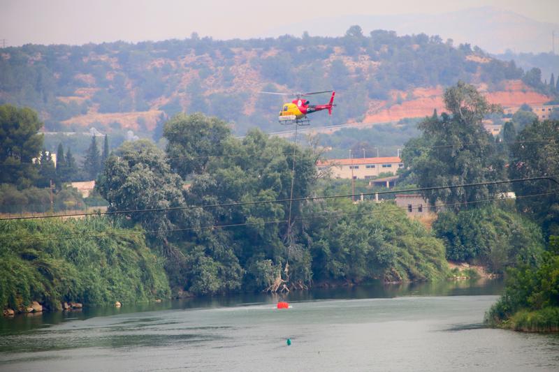 A firefighting helicopter collects water from the Ebre River, near Xerta