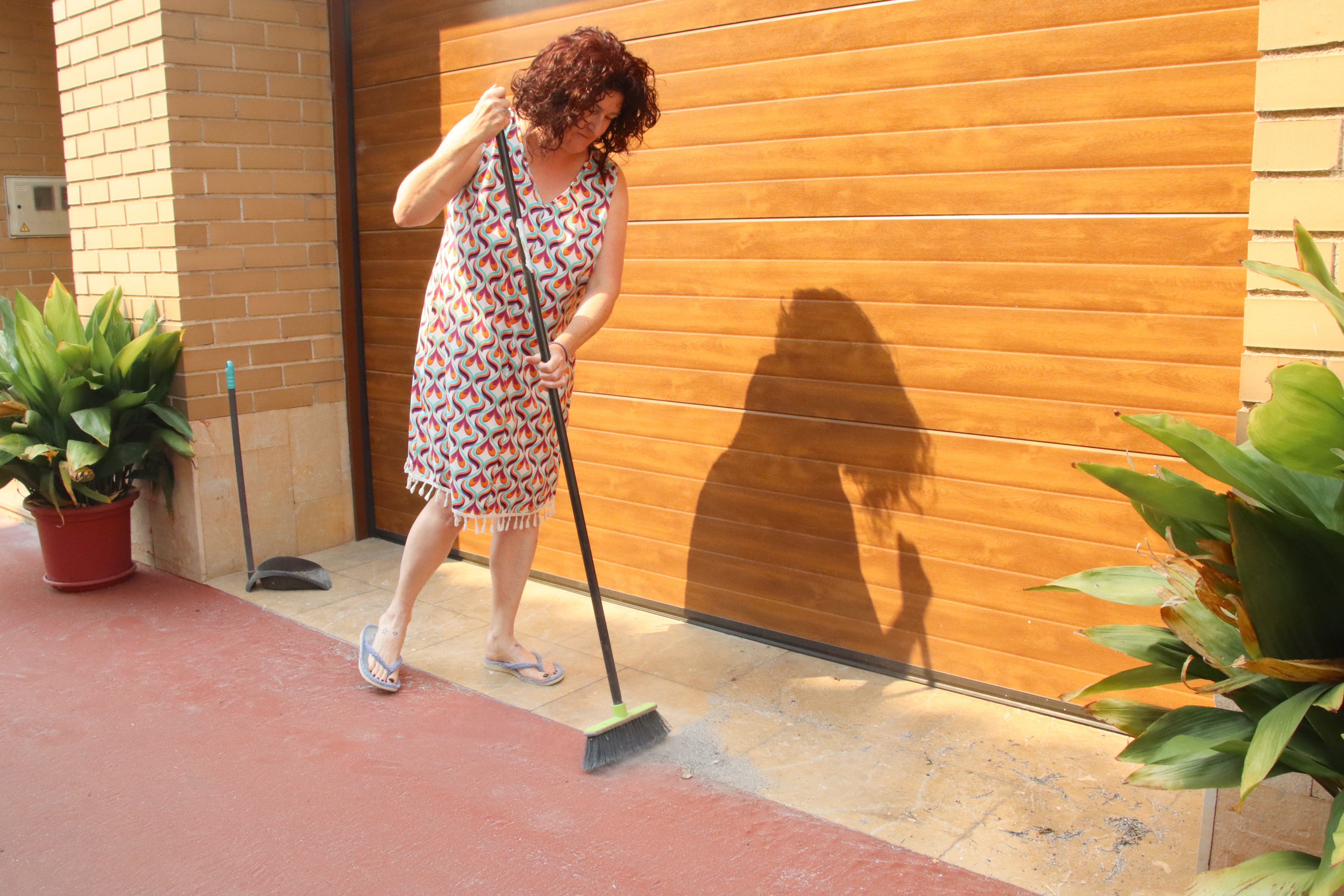 A neighbor in Aldover cleans ashes outside her home